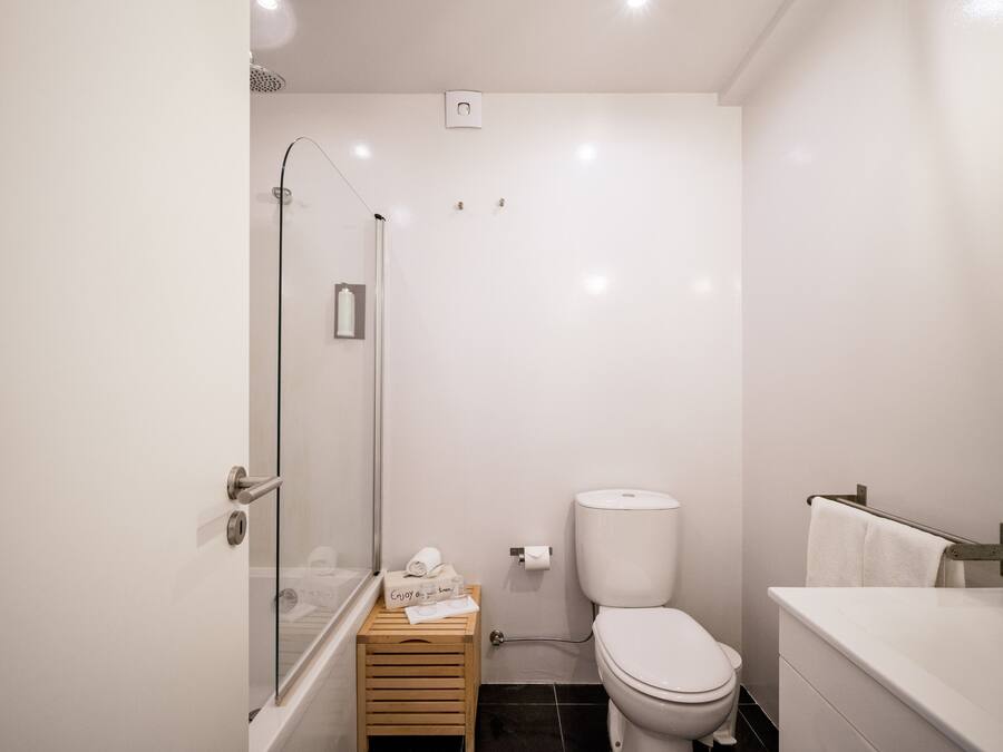 A modern bathroom with a glass shower enclosure, a toilet, and a bathtub.
