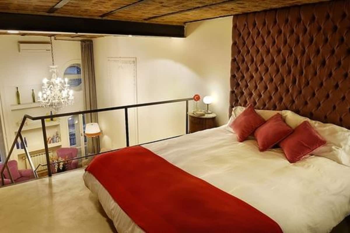A bedroom with a large bed, a red throw blanket, and a tufted headboard.