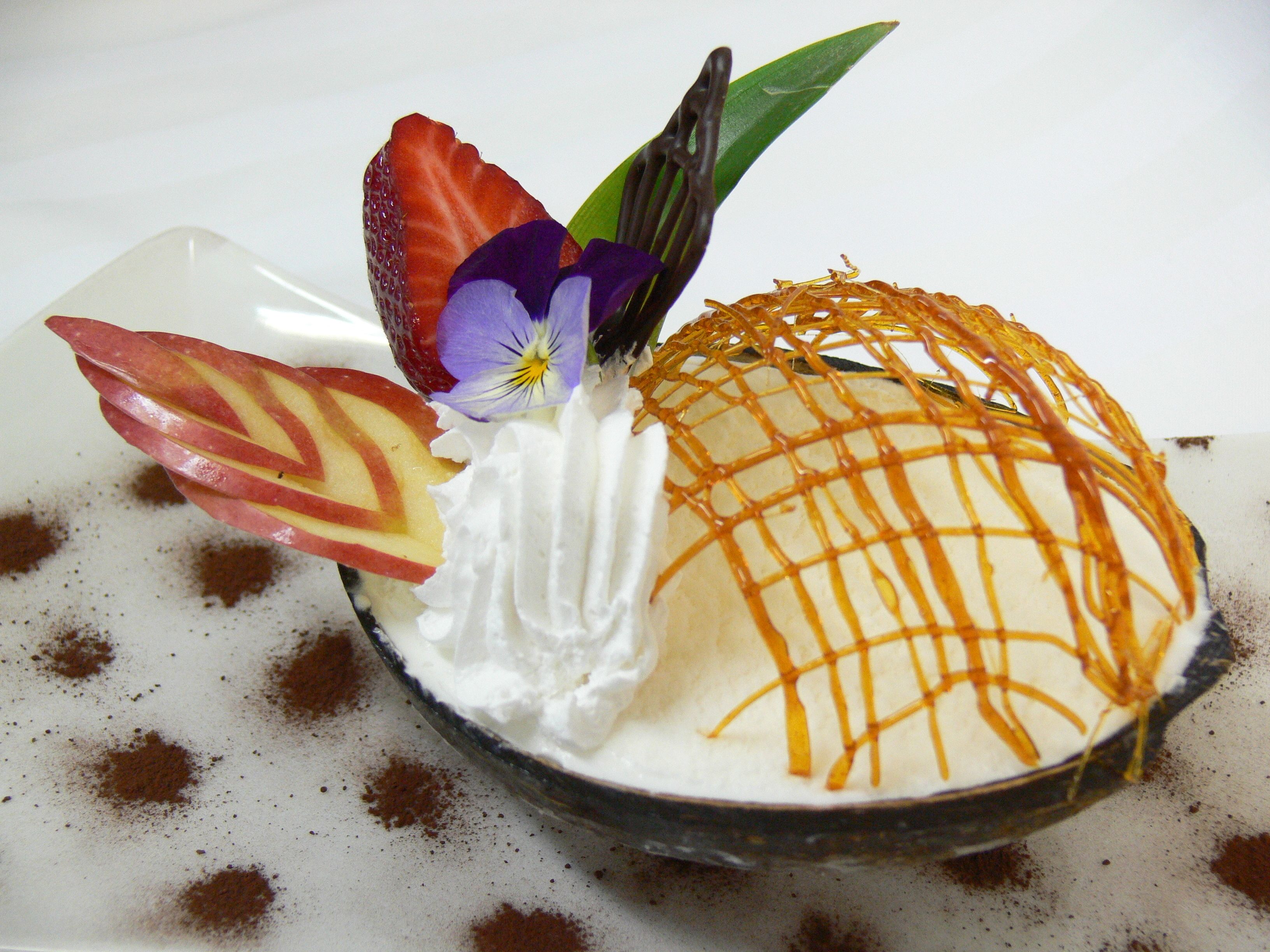 Un postre con crema batida, fruta y una cobertura caramelizada.