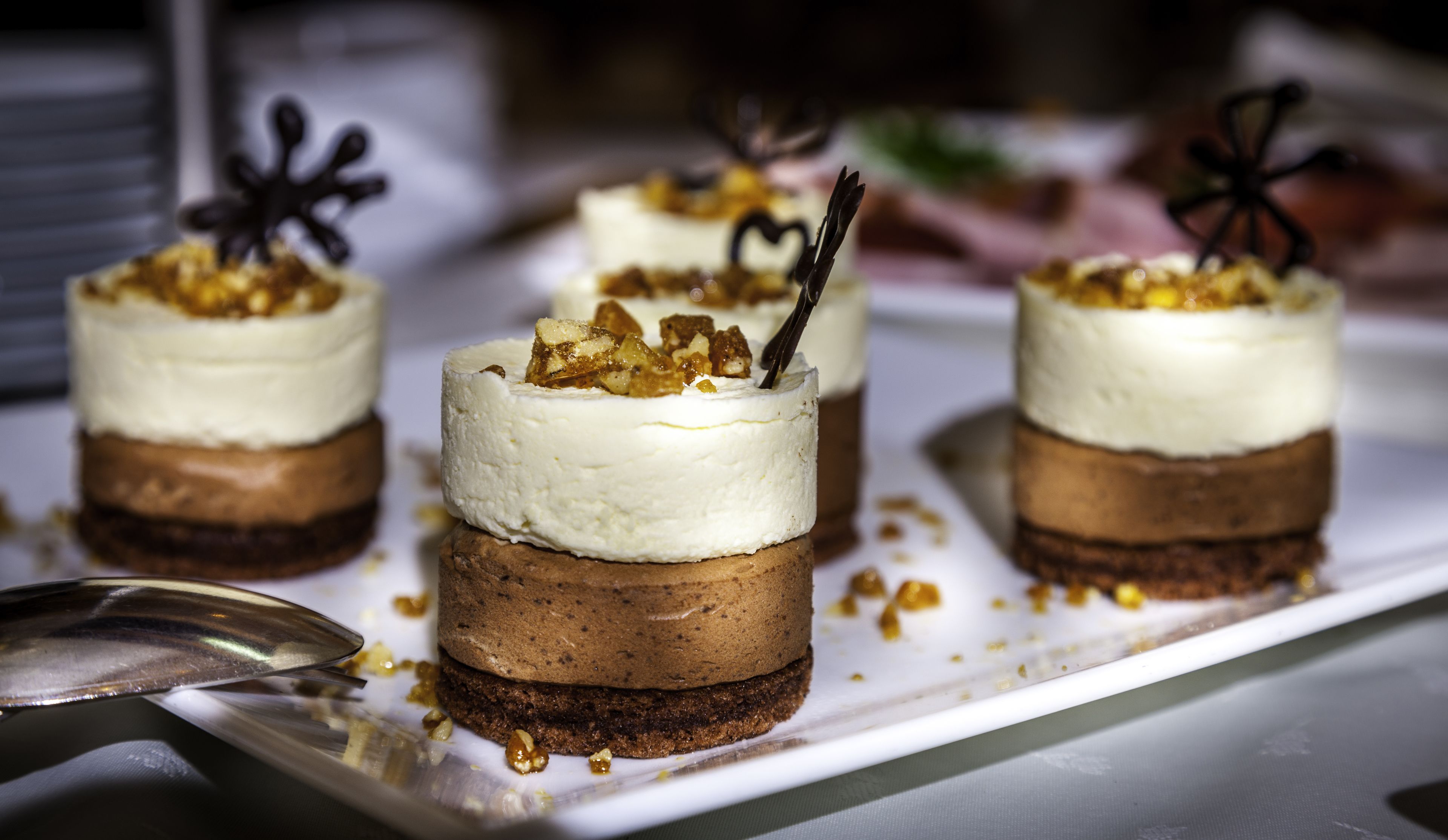 Un postre con capas de bizcocho y crema, decorado con nueces y un trozo de chocolate.