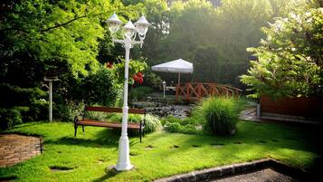 Un jardín con un banco, un farol y un pequeño puente.