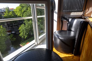 Una habitación con un ventanal grande, un sillón de cuero negro y una mesita.