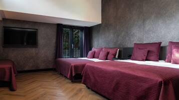 A hotel room with two beds, a flat-screen TV, and a large window with curtains.