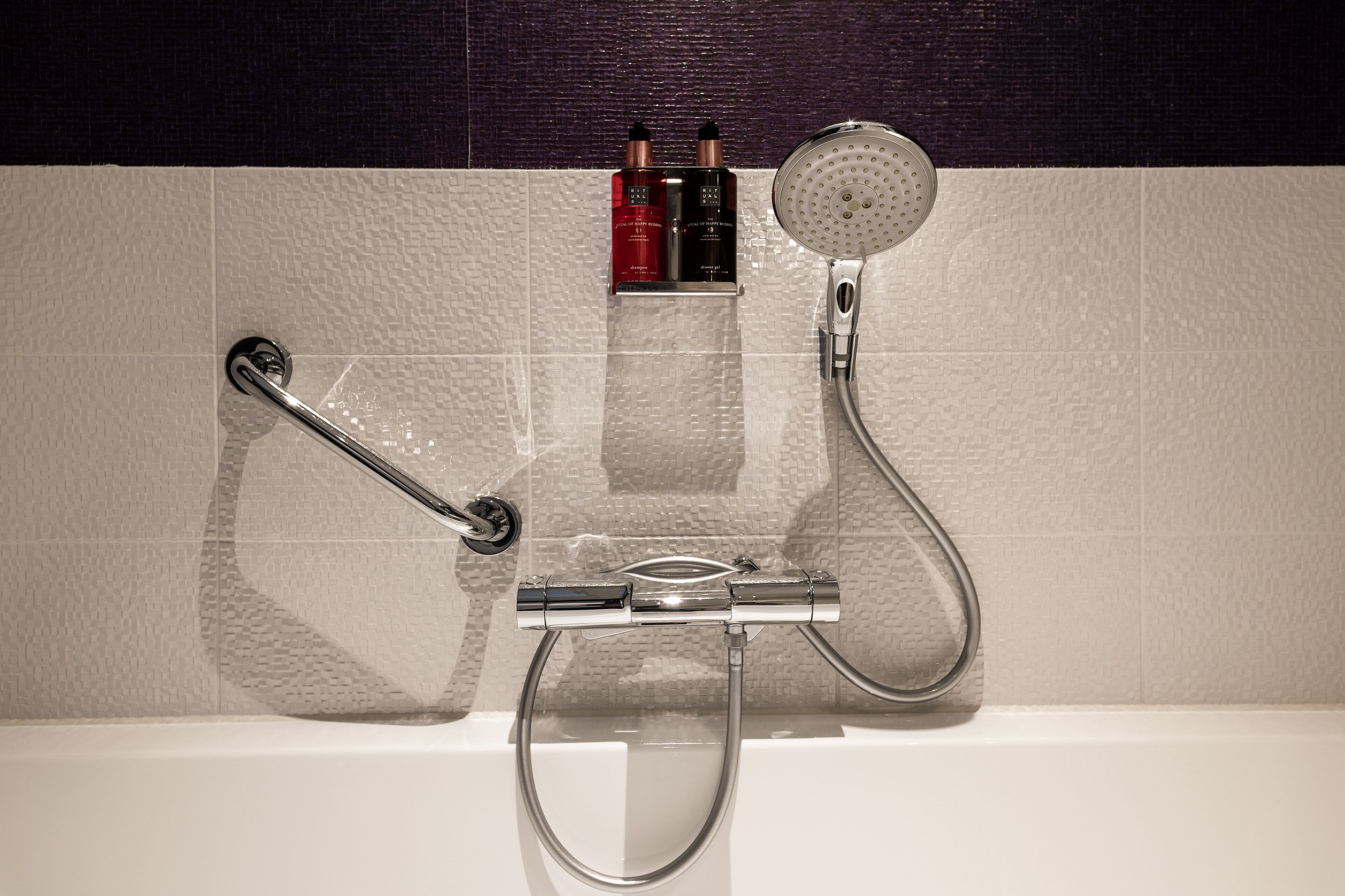 Une salle de bain équipée d’une douche, d’un pommeau de douche amovible et d’un robinet amovible.
