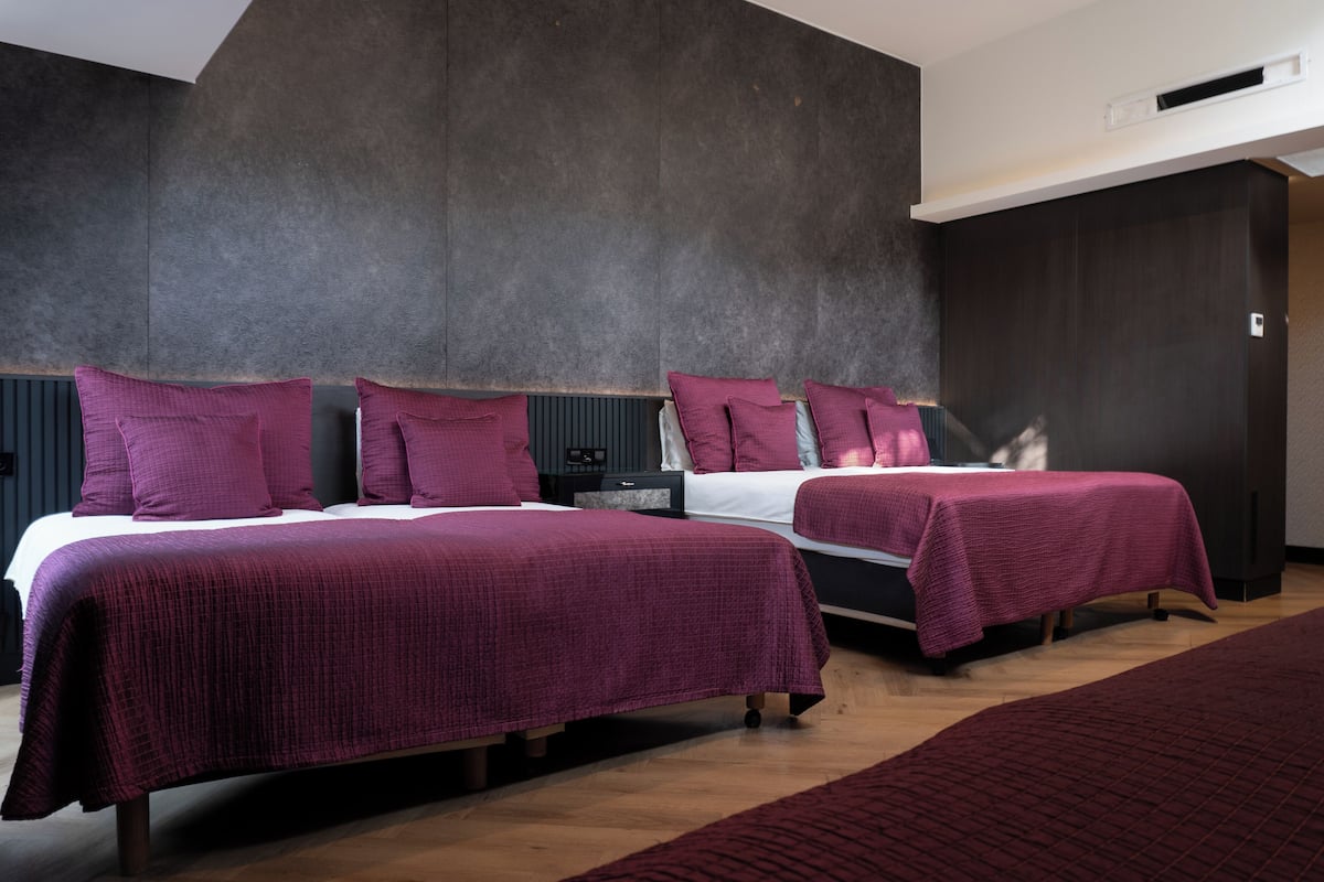 A hotel room with two beds, dark walls, and a wooden floor.