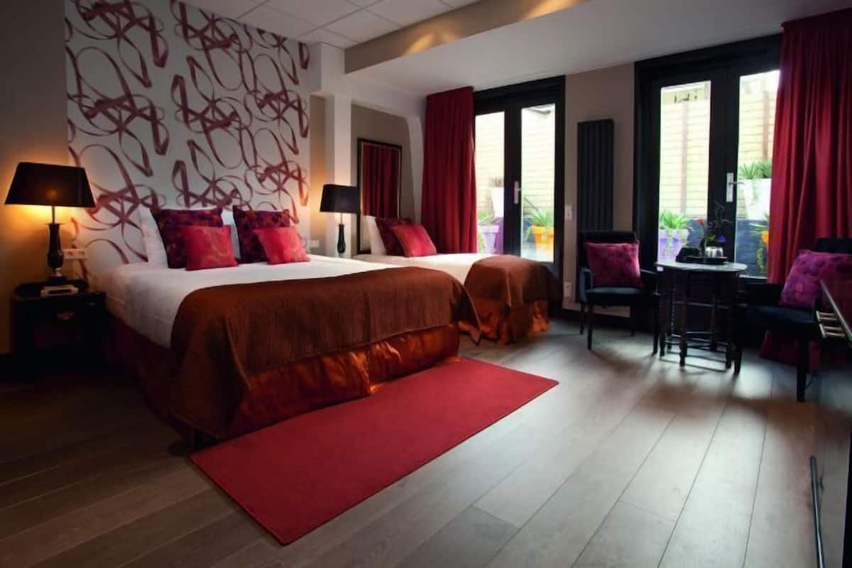 A hotel room with a large bed, two bedside tables, a desk, and a chair.