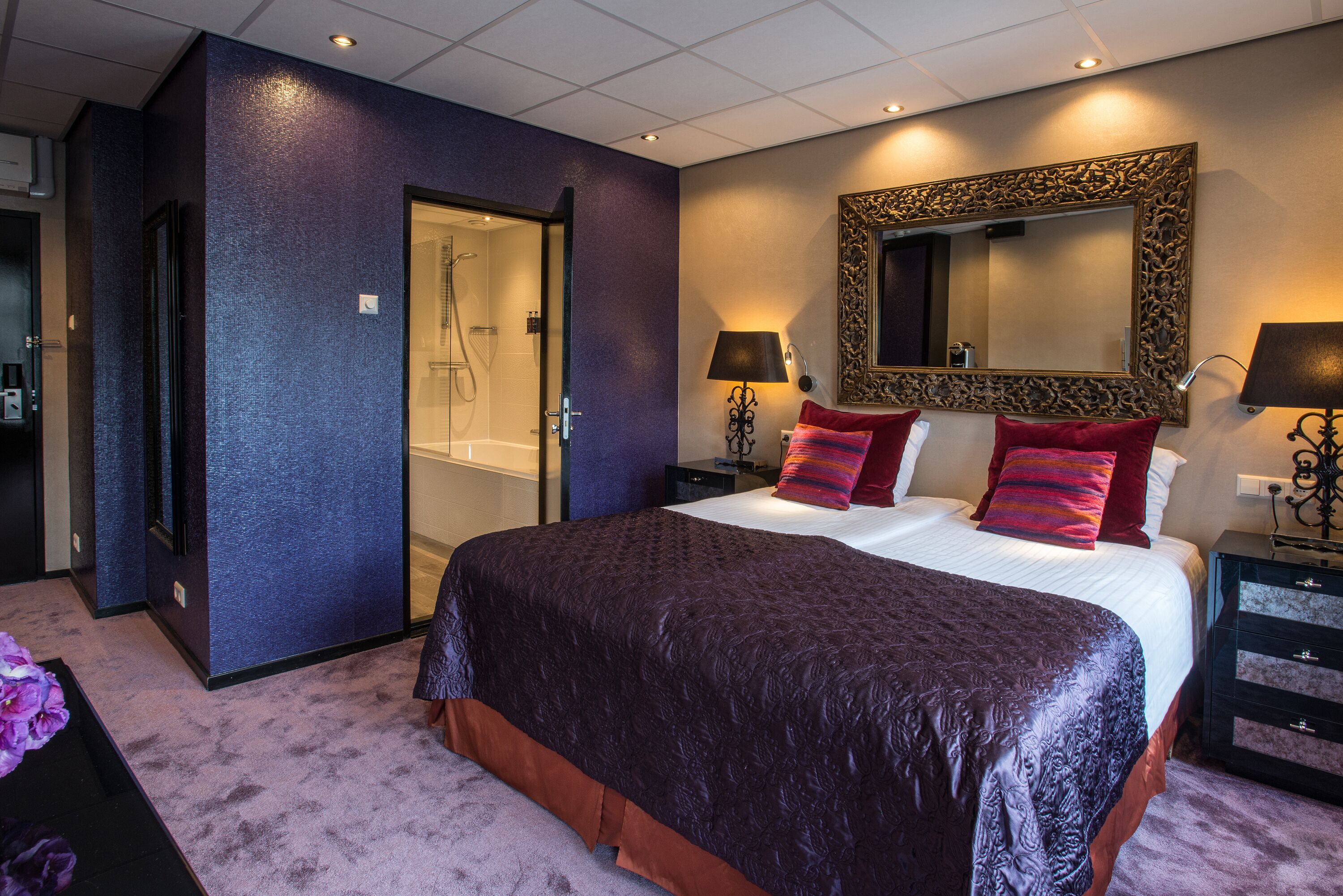A bedroom with a large bed, a shower, and a mirror on the wall.