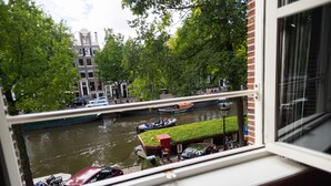 A view of a canal with boats, a green-roofed building, and a red car parked by the water. - Hotel Sebastian's (Amsterdam)