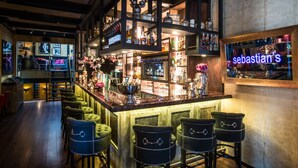 A bar area with multiple levels, bar stools, and a neon sign reading "sebastian's". - Hotel Sebastian's (Amsterdam)