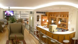 Un salon moderne doté d’un coin bar, comprenant un téléviseur, des sièges et un bar bien garni de bouteilles.