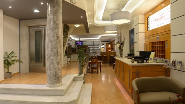 Un hall d’hôtel comprenant un comptoir d’accueil, un espace salon et un escalier menant à l’étage supérieur.