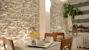 Un espace repas agrémenté d’un mur en pierre, d’une table en verre, de chaises en bois et d’un buffet.
