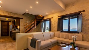 A modern living room with a beige sectional sofa, a wooden coffee table, and a view of the outdoors through large windows.