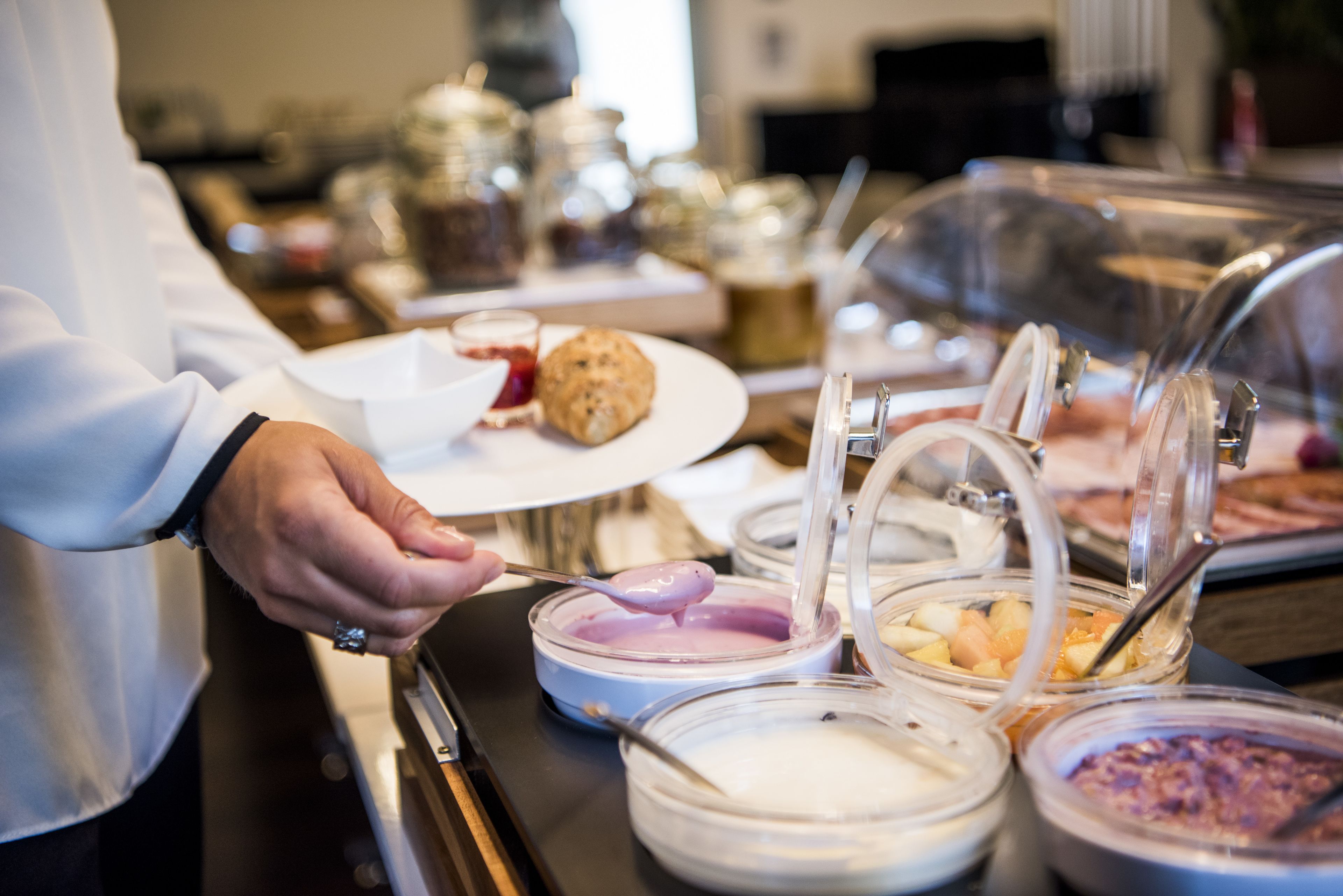 Un bufé con diversos alimentos y una persona servándose.