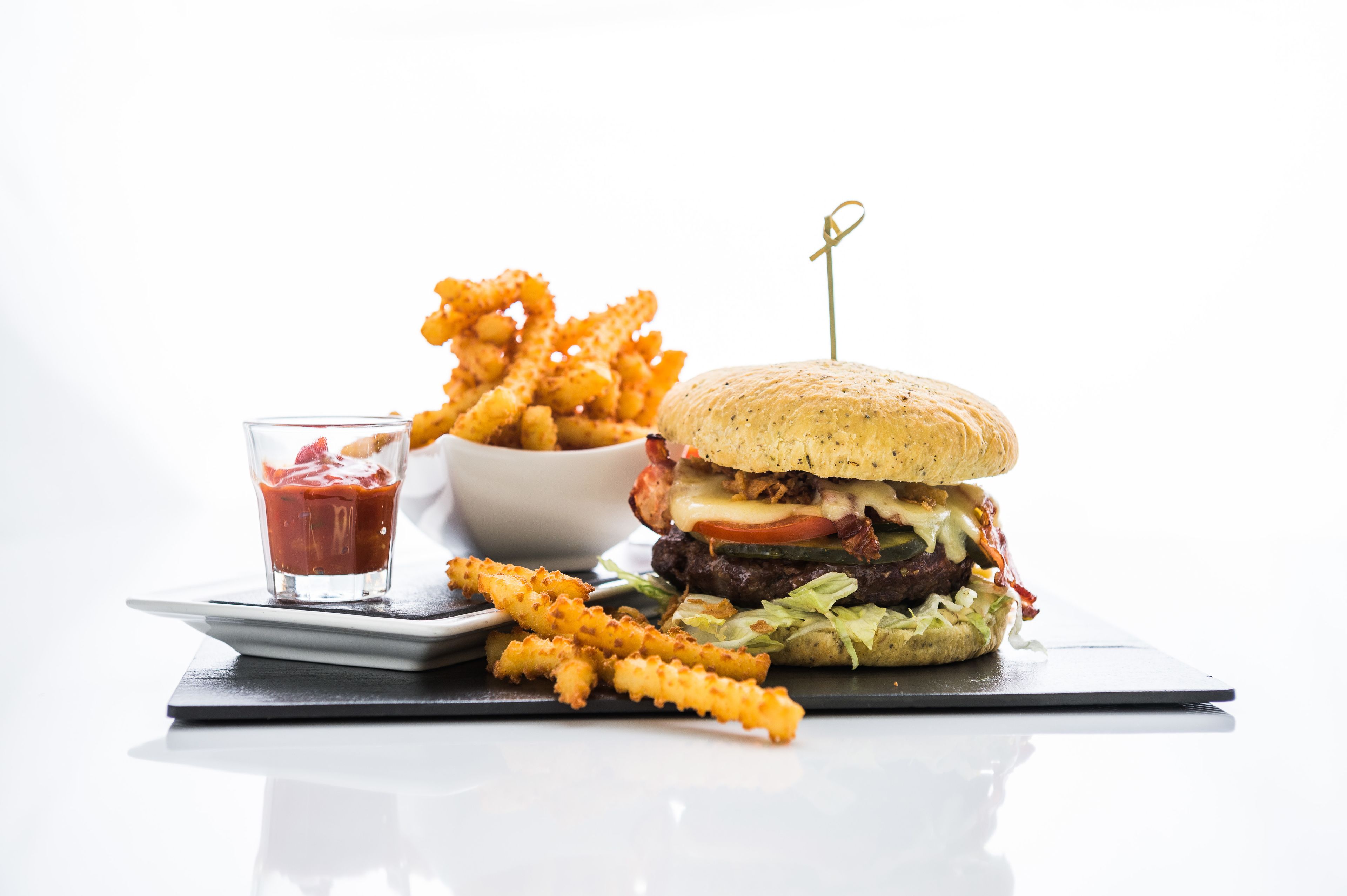 A burger with fries and ketchup on a white plate.