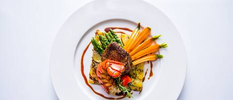 A white plate with a steak, asparagus, carrots, and a sauce.