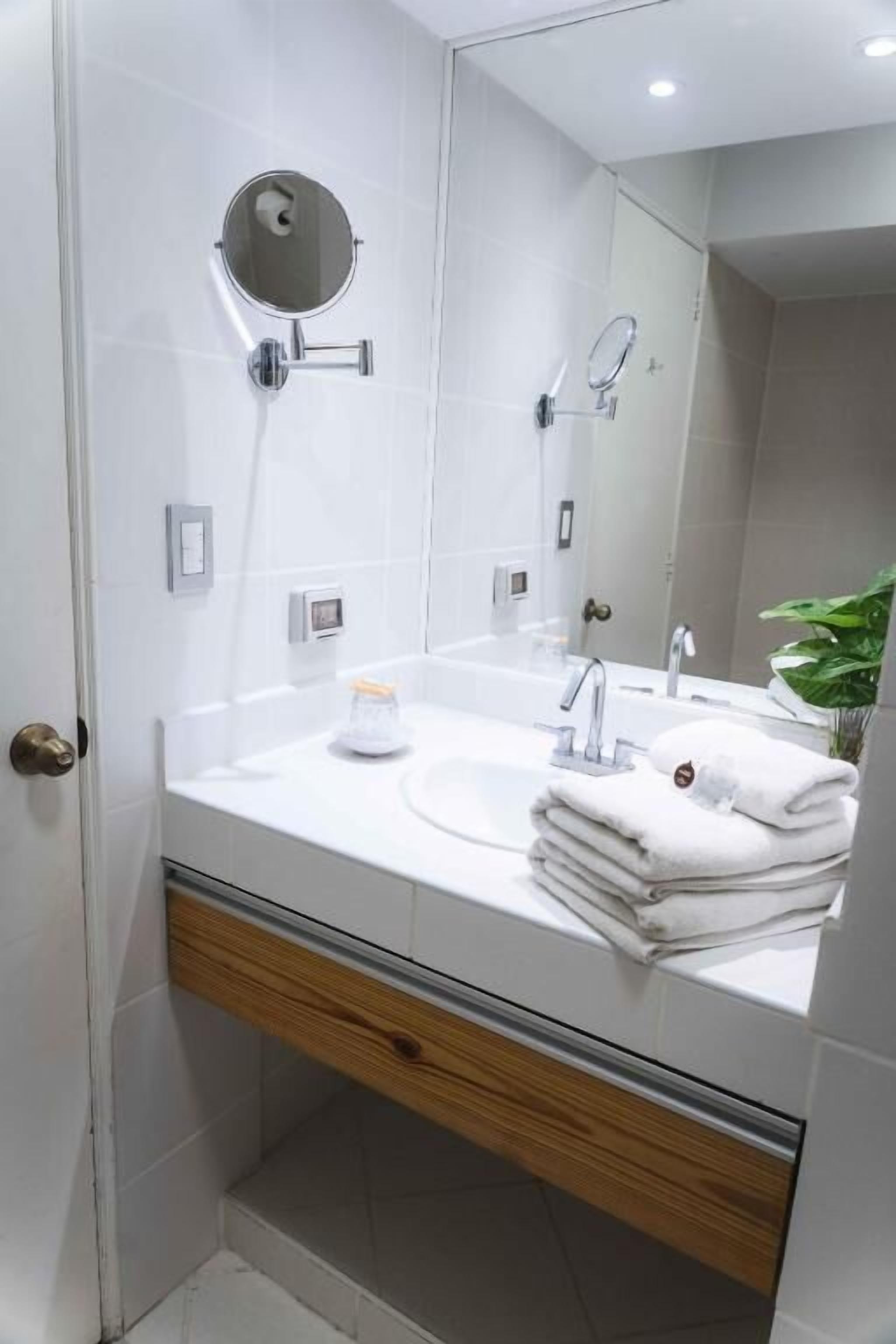 Ein modernes Badezimmer mit einem weißen Waschbecken, einem Spiegel und einem Handtuchhalter.