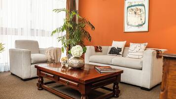 A living room with a beige sofa, a wooden coffee table, and a large plant.