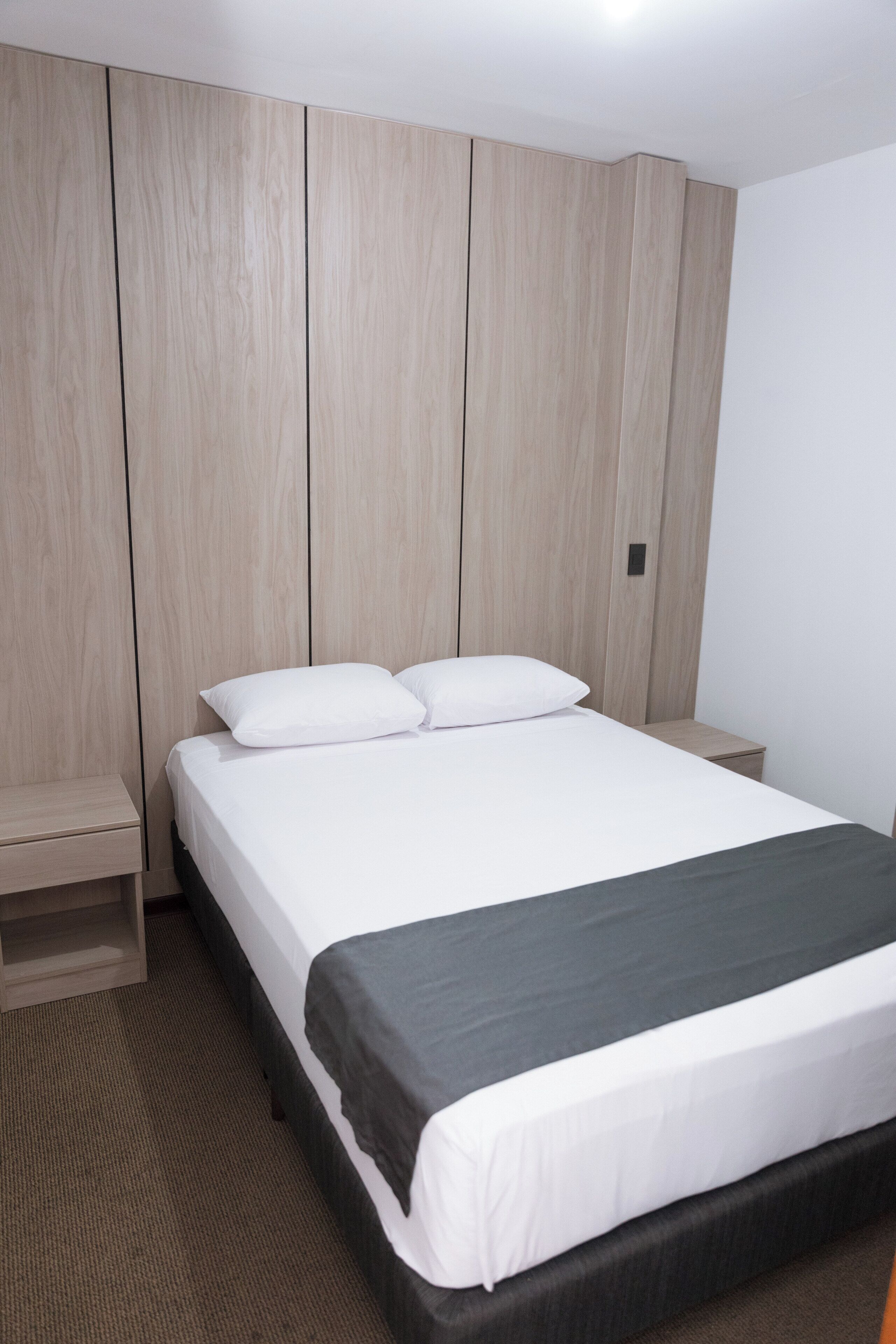A hotel room with a bed, a nightstand, and a wardrobe.
