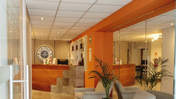 A reception area with a reception desk, seating area, and a glass wall. - La Paz Apart Hotel (Lima)
