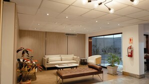 A modern interior with a sofa, bench, potted plants, and a fire extinguisher. - La Paz Apart Hotel (Lima)