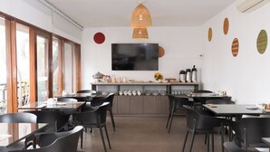 A modern dining area with black chairs, a central kitchen island, and a large TV on the wall. - La Paz Apart Hotel (Lima)
