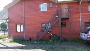 A red wooden building with a staircase leading to a second floor. - Hostal Emalafquen (Pucon)