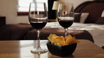 Two glasses of red wine and a bowl of chips on a table in a hotel room.
