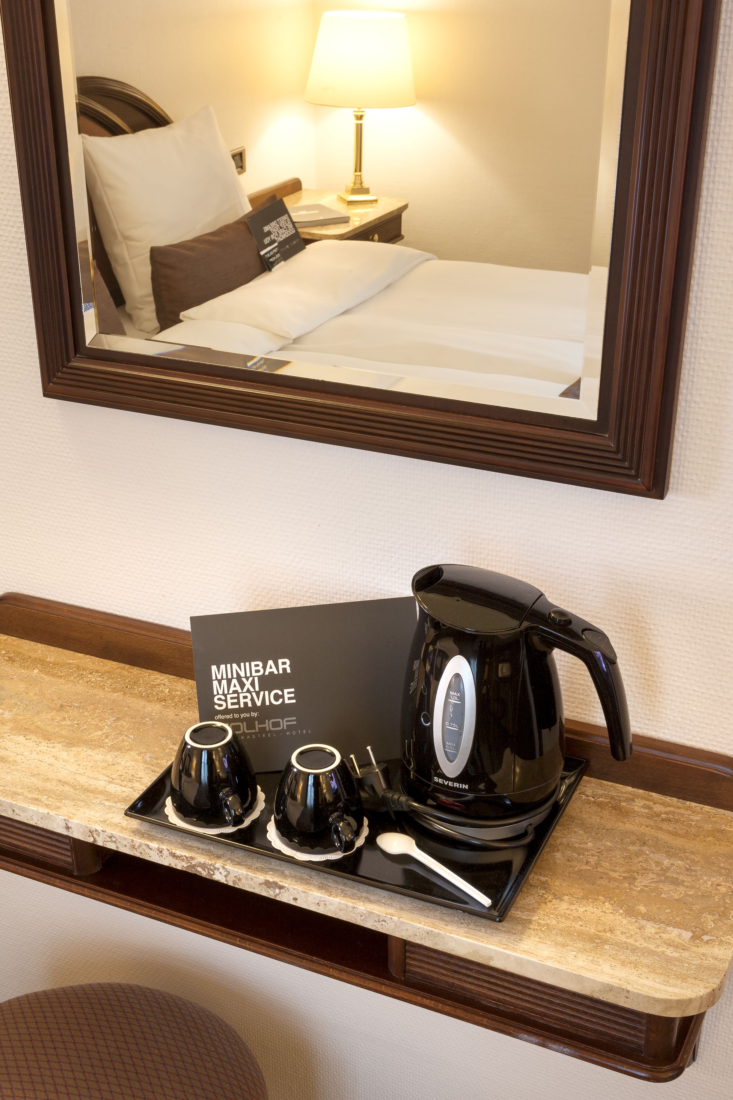Habitación de hotel con señal de servicio de minibar, una cafetera negra y dos tazas sobre una bandeja.