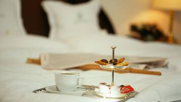 Una cama bien hecha con una bandeja que contiene una taza de café, un plato pequeño con pasteles y un objeto decorativo.