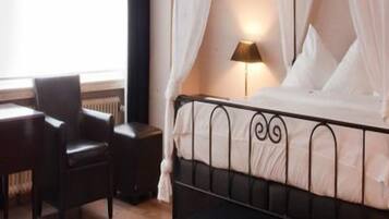 Una habitación de hotel con una cama, un escritorio, una silla y una mesita de noche con una lámpara.