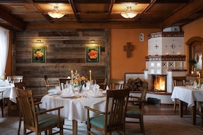 Un coin repas avec des murs en bois, une cheminée et une croix accrochée au mur.