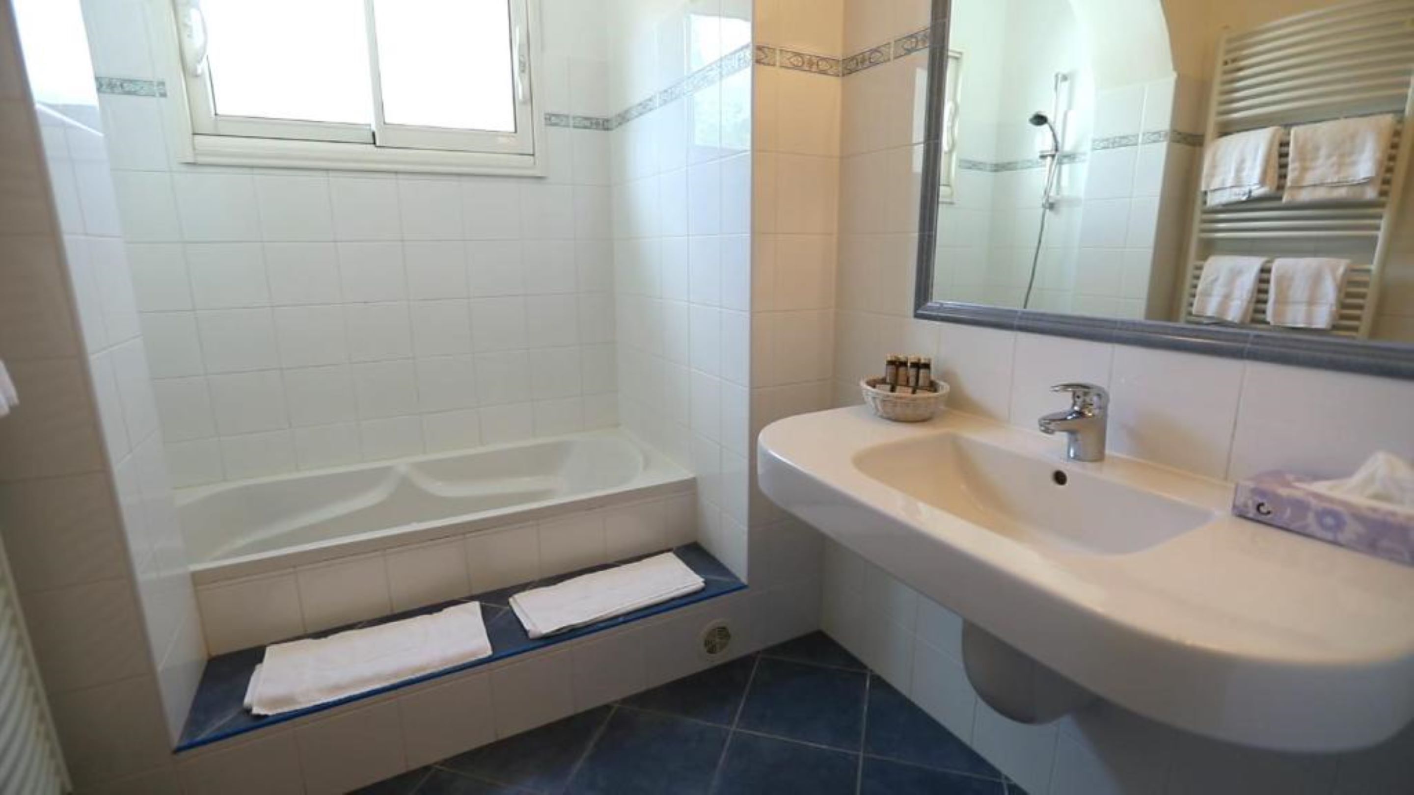 Un baño con bañera, lavamanos y espejo.