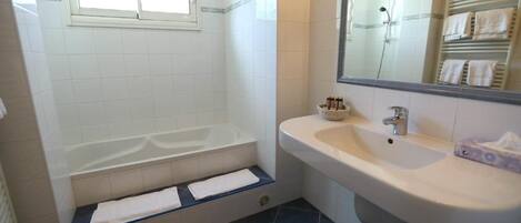 A bathroom with a bathtub, a sink, and a mirror.