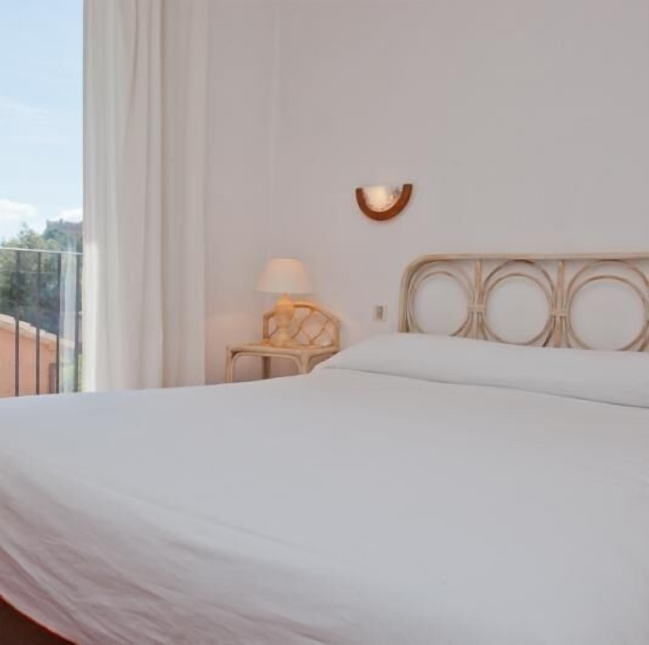 Une chambre d’hôtel avec un grand lit, une table de chevet avec une lampe et une vue sur l’extérieur.