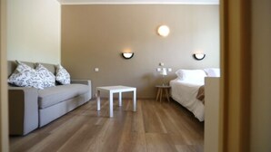 A hotel room with a sofa, a small table, a bed, and two wall-mounted lamps. - Sole e Monti (Quenza)