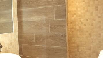 A modern bathroom with a large mirror, a white sink, and a shower area.
