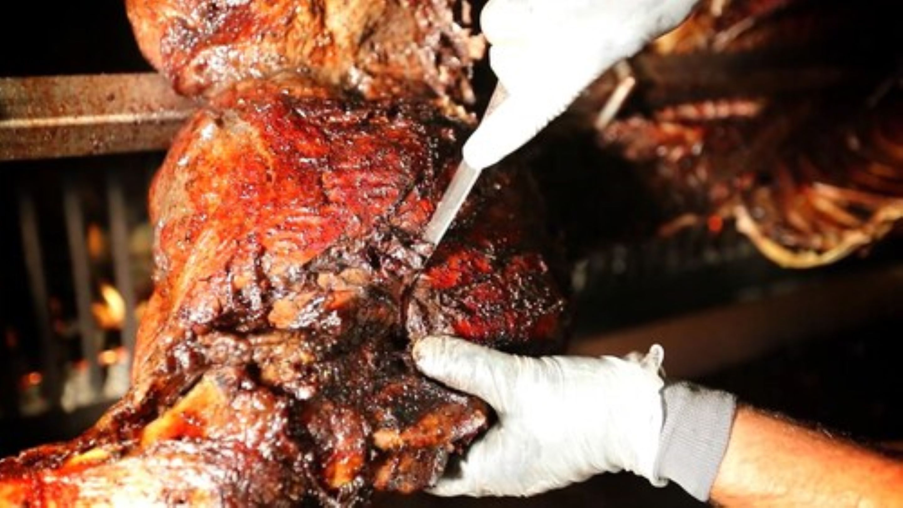A close-up of a person carving a large, roasted meat.