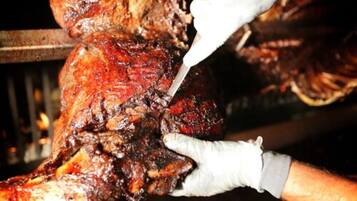 A close-up of a person carving a large, roasted meat.