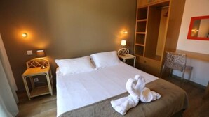 A hotel room with a large bed, two bedside tables with lamps, a wardrobe, and a chair. - Sole e Monti (Quenza)