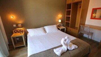 Quarto de hotel com uma cama grande, duas mesas de cabeceira com luminárias, um guarda-roupa e uma cadeira.