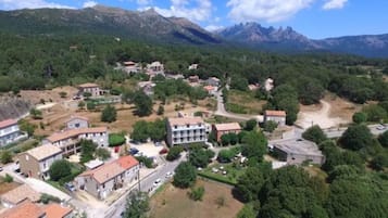 An aerial view of a residential area with houses, roads, and a mountainous backdrop.