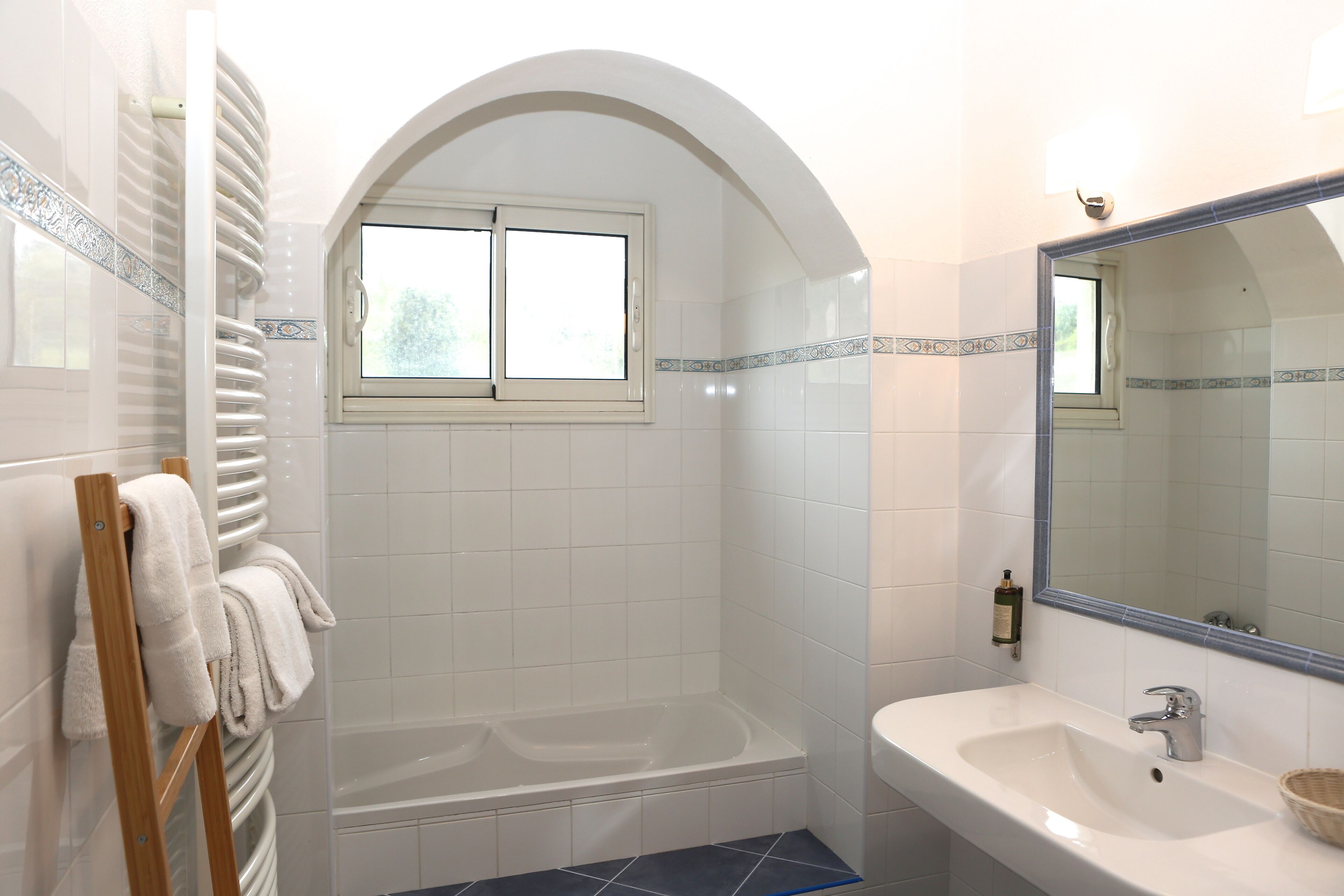 Une salle de bain avec une baignoire, un lavabo et une fenêtre.