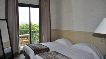 A hotel room with two beds, a balcony with a view, and a large window.