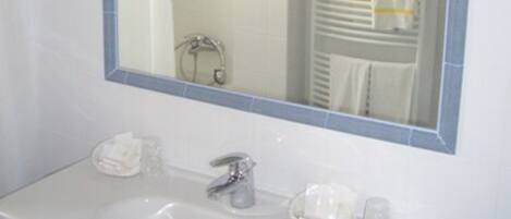 Un baño con un lavamanos blanco, un espejo y un perchero para toallas.