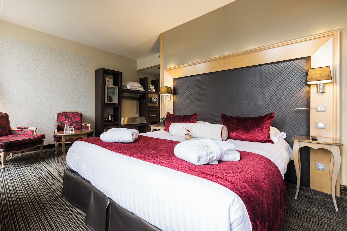 Una habitación de hotel con una cama grande, un escritorio, una silla y un armario.