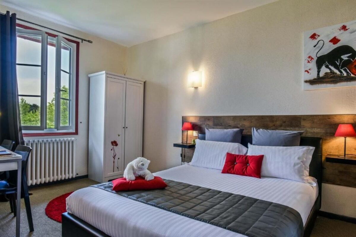A hotel room with a bed, a desk, a radiator, a wardrobe, and a window with curtains.