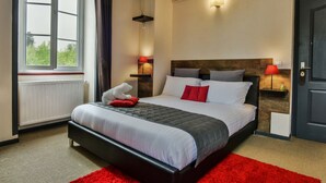 A neatly arranged bedroom with a large bed, two bedside tables with lamps, a radiator, and a window with curtains. - Auberge L'Estanquet (Urt)