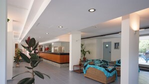 Um hall amplo com balcão de recepção, área de estar e plantas em vasos.
