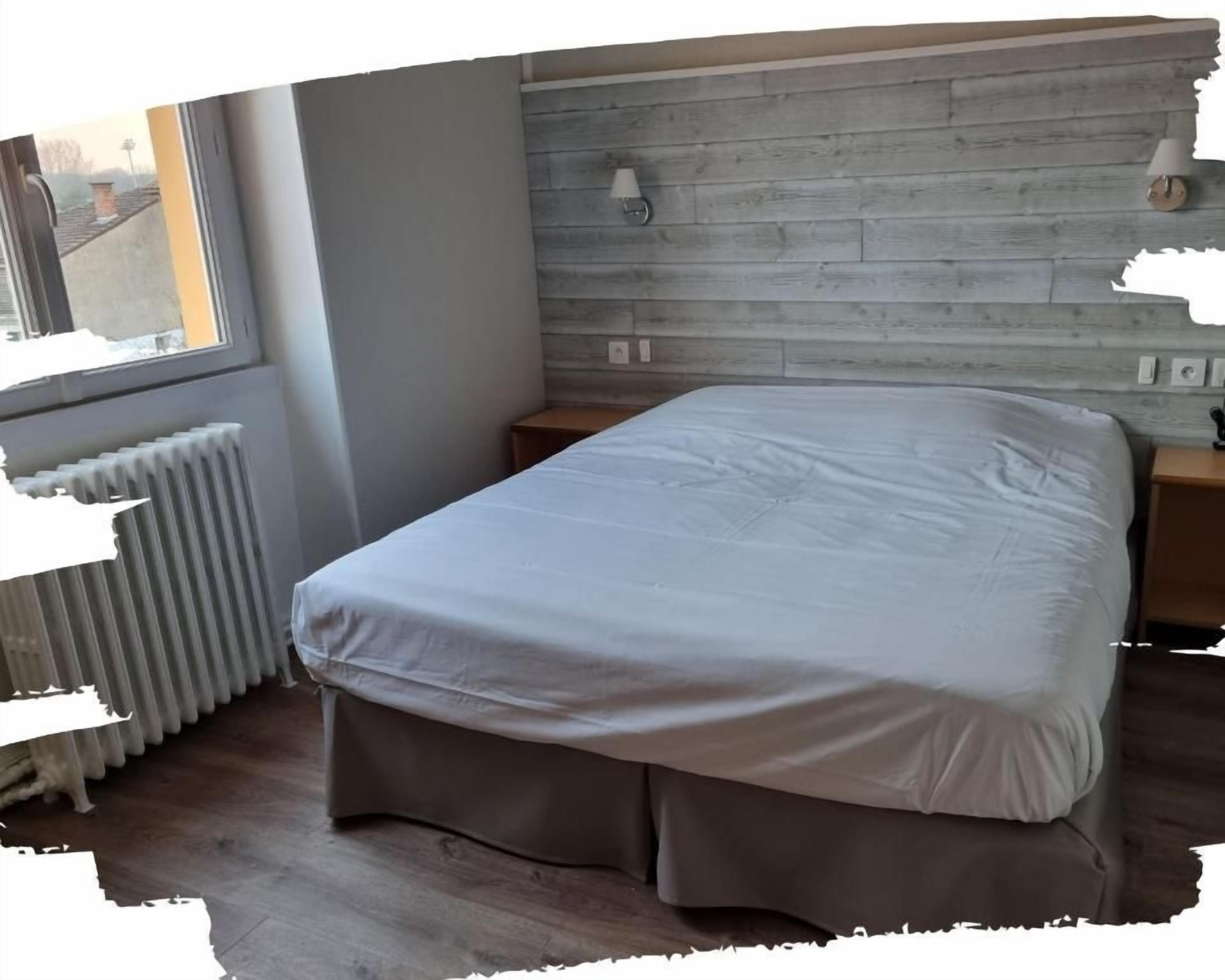 A bedroom with a bed, a radiator, a window, and a wooden headboard.
